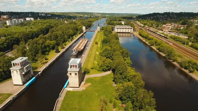 Sluice Gates on the River. Aerial view barge, ship in the river gateway. River sluice construction, water river gateway. Shipping channel. 4K, flying video, aerial footage