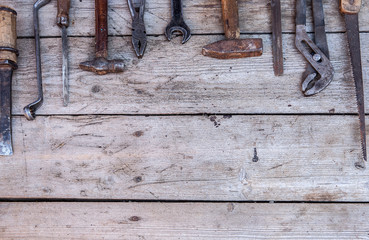 Old, rusty tools lying on a black wooden table. Hammer, chisel, hacksaw, metal wrench.Copy space