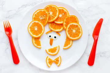 Funny man face from orange slices, healthy fruit snack for kids