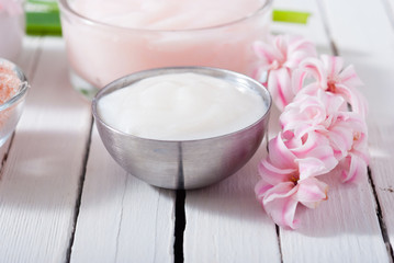 beauty and cosmetic creams with pink flowers on white wood