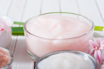 beauty and cosmetic creams with pink flowers on white wood