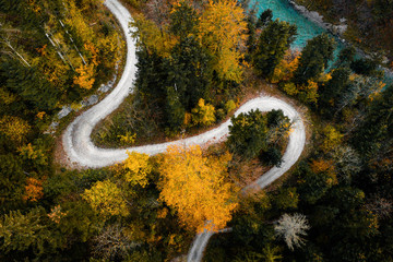 Serpentinenstraße durch einen Wald mit einem Fluss daneben in den bayerischen Alpen im Herbst bei...