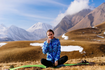 active sports girl in a blue jacket sits on the background of the Caucasus mountains, loves to...
