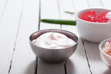 beauty and cosmetic creams with pink flowers on white wood