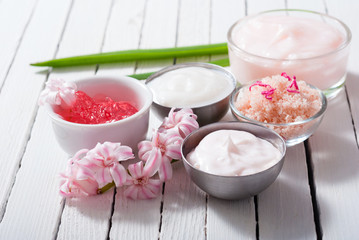 beauty and cosmetic creams with pink flowers on white wood