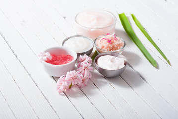 beauty and cosmetic creams with pink flowers on white wood