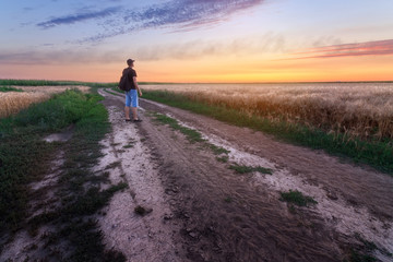 Obraz premium trail on the field during sunset / man watching the sunset evening landscape