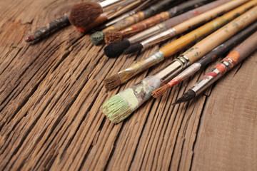 Artistic paintbrushes on the old wooden background