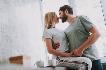 Waist up of a joyful young couple kissing and expressing love