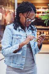 Young woman dressed in casual clothes in the mall with a phone