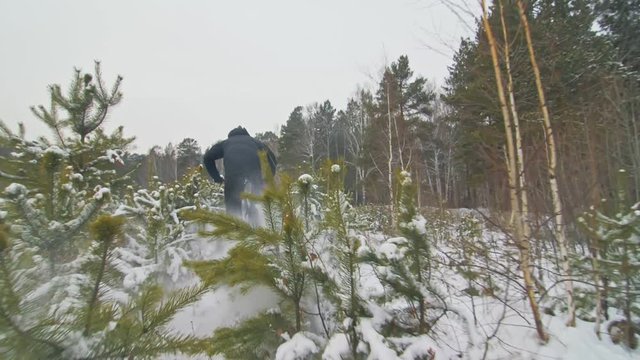 Professional extreme sportsman biker cool riding fat bike in outdoors. Extremal ride through an pine trees. Man does trick on mountain bicycle with big tire in helmet, glasses. Slow motion in 180fps.