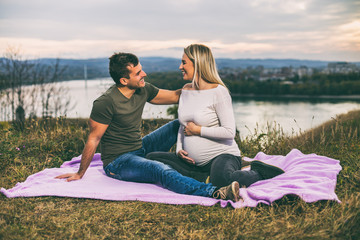 Fototapeta na wymiar Husband and pregnant wife enjoy spending time together outdoor.
