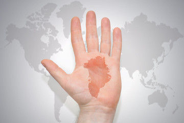 hand with map of greenland on the gray world map background.