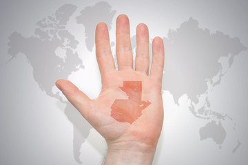 hand with map of guatemala on the gray world map background.