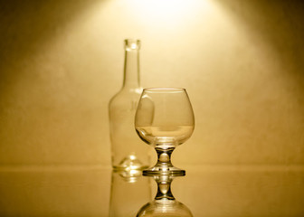 Empty brandy glass on the background of the bottle. Highlighting top.