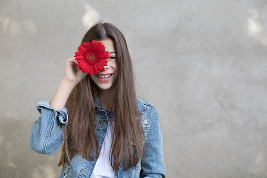 Portrait of laughing girl with flower head of red Gerbera