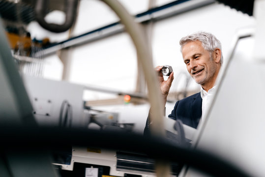 Manager in high tech enterprise, checking machine parts