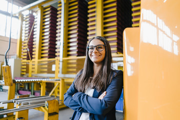 Confident woman standing in logistics center, with arms crossed