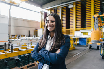 Confident woman standing in logistics center, with arms crossed