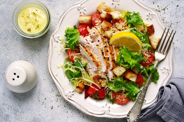 Caesar salad with grilled chicken, parmesan cheese, croutons and cherry tomatoes.Top view with copy space.
