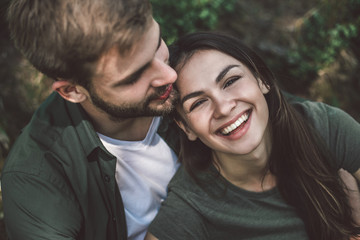 Take a break and relax in journey. Close up top view portrait of happy young man and woman sitting in arms of each other on green land