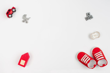 Red baby shoes and wooden toys on white background with copy space
