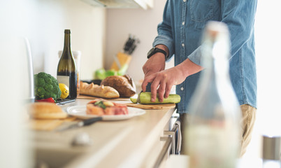 One more ingredient. Close up of male arms chopping vegetables with knife for dinner