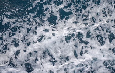 Fototapeta na wymiar Top view on a foamy sea surface shot from above on a ferry boat travel cruise