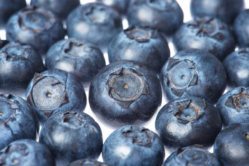 Aerial red raspberries and dark blue blueberries on a light substrate. White background.