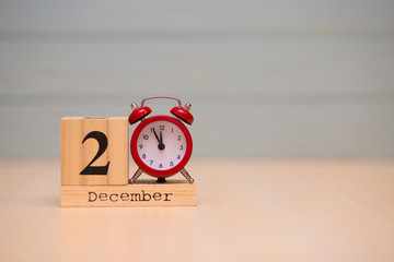 December 2nd set on wooden calendar and red alarm clock with blue background.