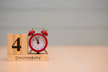 December 4th set on wooden calendar and red alarm clock with blue background.