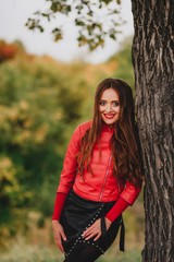 Beautiful girl in red leather jacket in autumn forest.