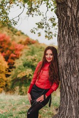 Fototapeta na wymiar Beautiful girl in red leather jacket in autumn forest.