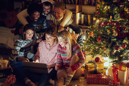 friends watching laptop by Christmas tree