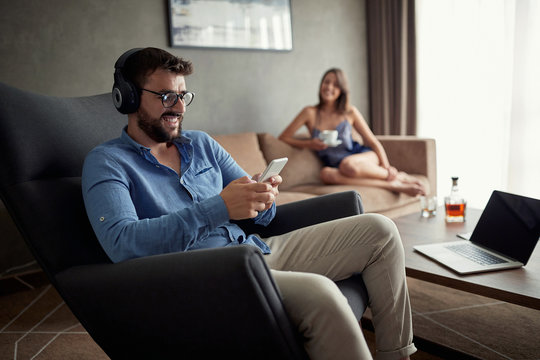 man uses a phone to listen to music and relax at home.