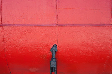 Paint smudges on the surface. Bright red background. Painted metal surface. Metal painted in red. Red metal sheets. Old painted surface. The black item on the red surface.