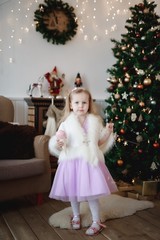 Lovely girl in purple dress in the background of Christmas decorations.