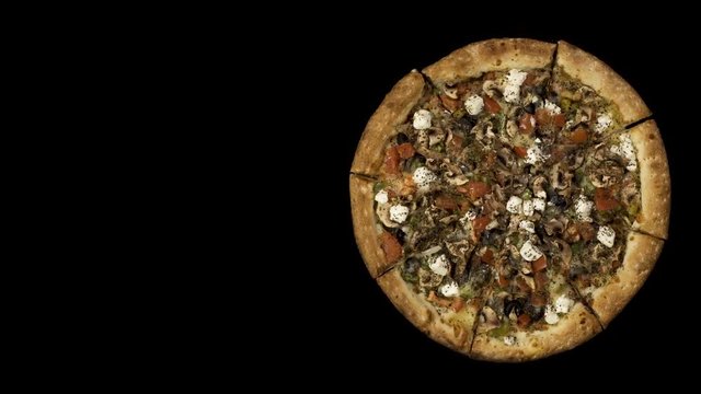 Rotating pizza with smoked sausage and olives on a black background. Top view center orientation