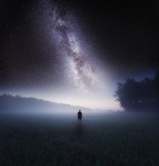 Dreamy surreal landscape with starry night sky and man silhouette