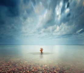 Hand of drawning man sticking out of the water
