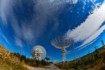 Array of satellite dishes or radio antennas against sky. Space o