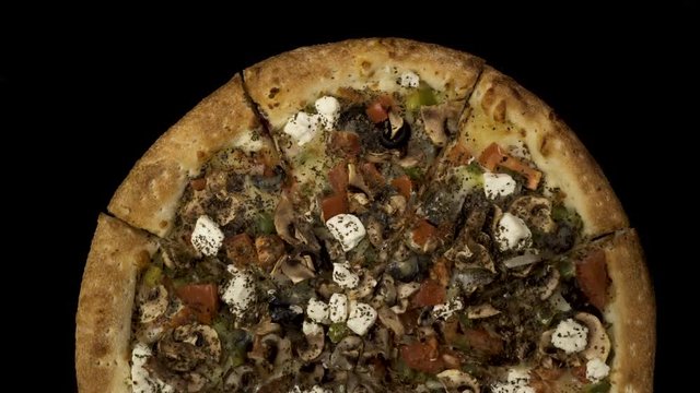 Rotating pizza with smoked sausage and olives on a black background. Top view center orientation