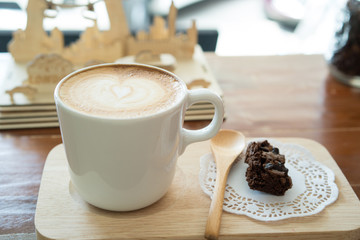 Hot latte art coffee and Chocolate brownie on wood table