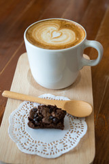 Hot latte art coffee and Chocolate brownie on wood table