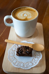 Hot latte art coffee and Chocolate brownie on wood table