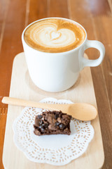 Hot latte art coffee and Chocolate brownie on wood table