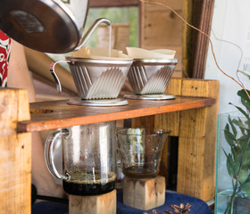 Barista pouring hot water on roasted coffee ground with filter.