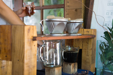 Barista pouring hot water on roasted coffee ground with filter.