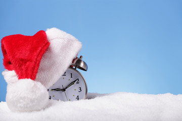 Alarm clock with Santa hat outdoors in snow