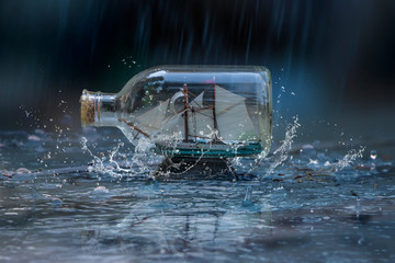 Glass bottle with ship miniature inside in the rain